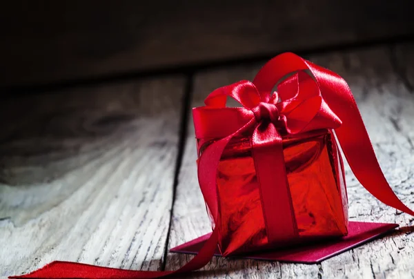 Caja de regalo roja atada con una cinta escarlata con lazo —  Fotos de Stock