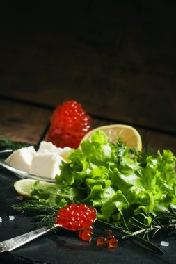 Bir gümüş kaşık siyah bir taş zemin üzerine kırmızı somon havyar  