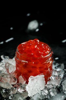 Delicious red caviar in a glass jar on crushed ice 