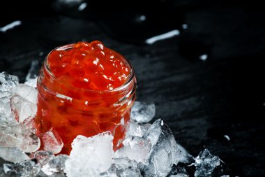 Delicious red caviar in a glass jar on crushed ice 