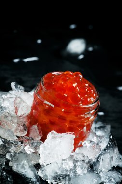 Delicious red caviar in a glass jar on crushed ice 