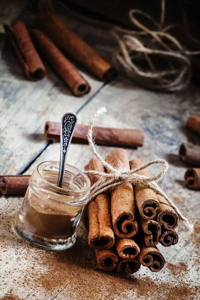 Ground cinnamon, cinnamon sticks, tied with jute rope — Stockfoto