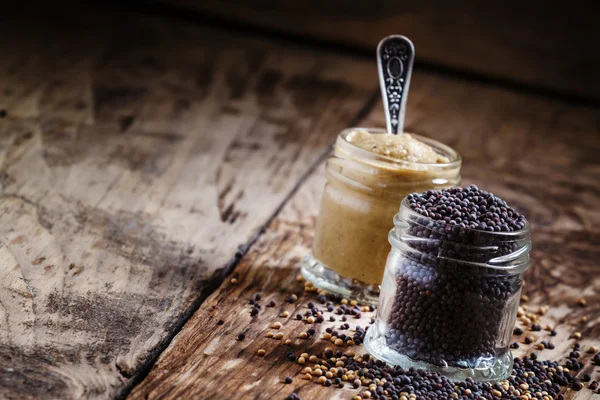 Moutarde dans un bocal en verre et graines noir et jaune — Photo