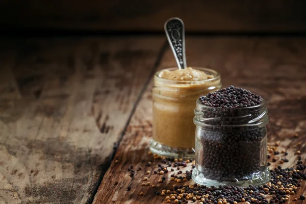 Mostaza en un frasco de vidrio y semillas negro y amarillo — Foto de Stock