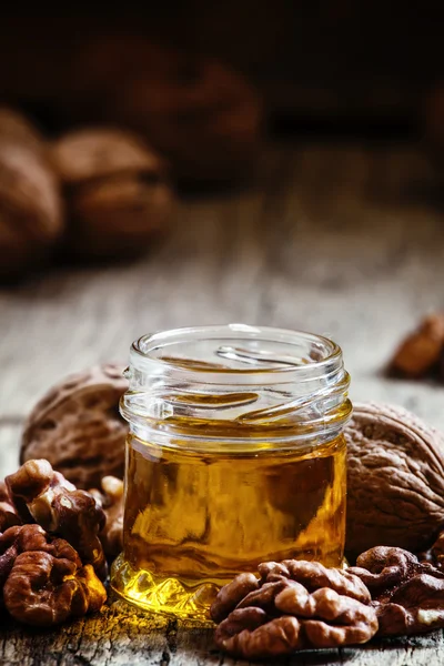 Aceite de nuez en un frasco pequeño y granos —  Fotos de Stock