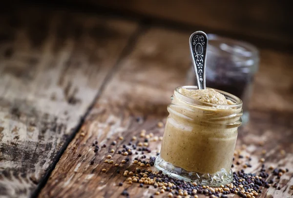 Mosterd in een glazen pot en zaden zwart en geel — Stockfoto