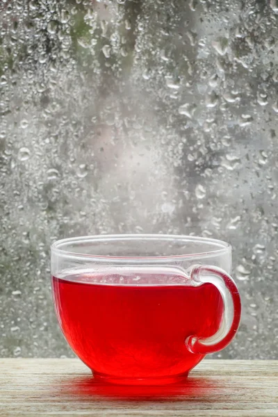 Taza con té rojo caliente frente a una ventana — Foto de Stock