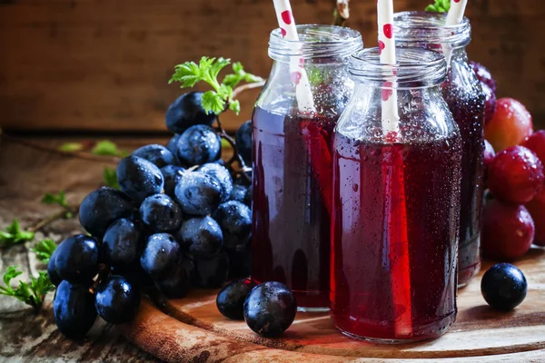 Saft aus dunklen Trauben in kleinen Glasflaschen — Stockfoto