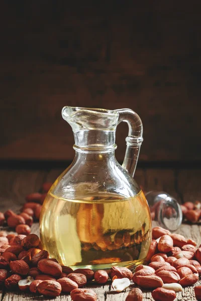 Арахисовое масло в стакане кувшин и пролитые орехи — стоковое фото
