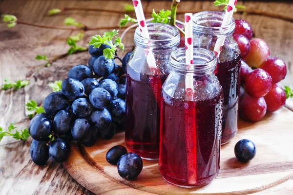 Сок из темного винограда в маленьких стеклянных бутылках — стоковое фото