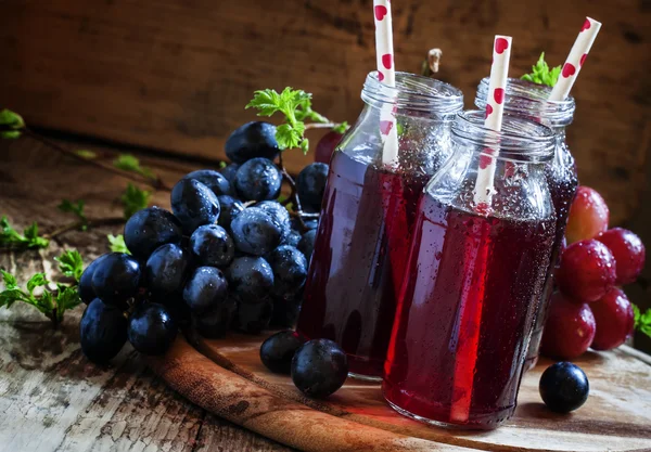 Juice från mörka druvor i små glasflaskor — Stockfoto