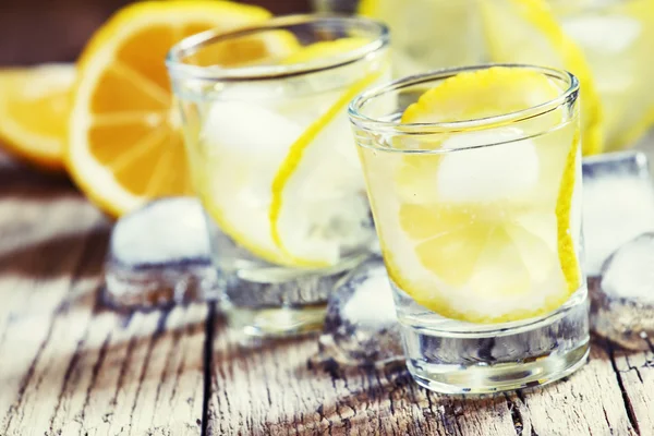 Vodka russa fria com limão e gelo em copos de tiro — Fotografia de Stock