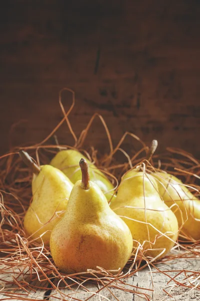 Yellow pears in the dry straw on the vintage wooden table — Stock Photo, Image