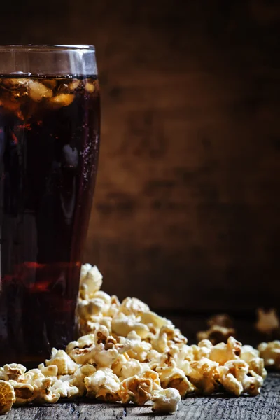 Großes Glas Cola, salziges Popcorn auf den Tisch geschüttet — Stockfoto