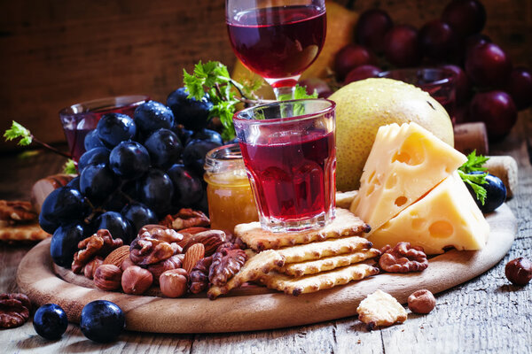 Rose wine and wooden dish with various snacks