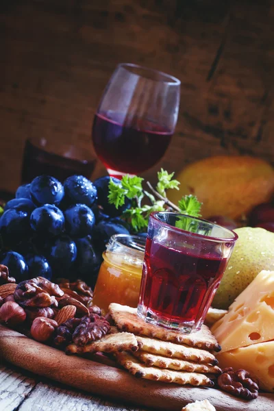 Vino rosa y plato de madera con varios aperitivos — Foto de Stock