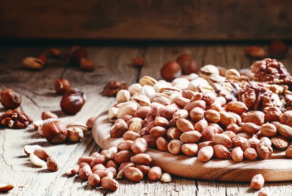 Verschüttete Erdnüsse, dunkler Hintergrund aus Holz — Stockfoto