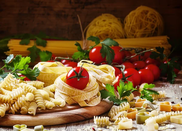 Diverse droge pasta, cherry tomaten en peterselie — Stockfoto