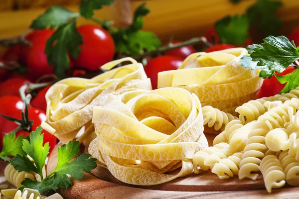 Diverse droge pasta, cherry tomaten en peterselie — Stockfoto