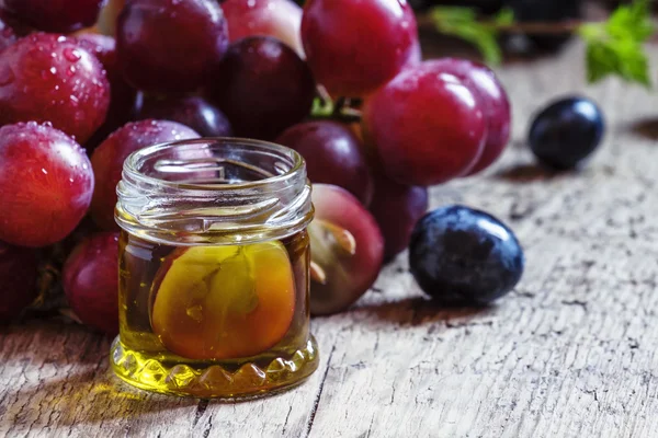 Aceite esencial de semillas de uva y un racimo de uvas frescas —  Fotos de Stock