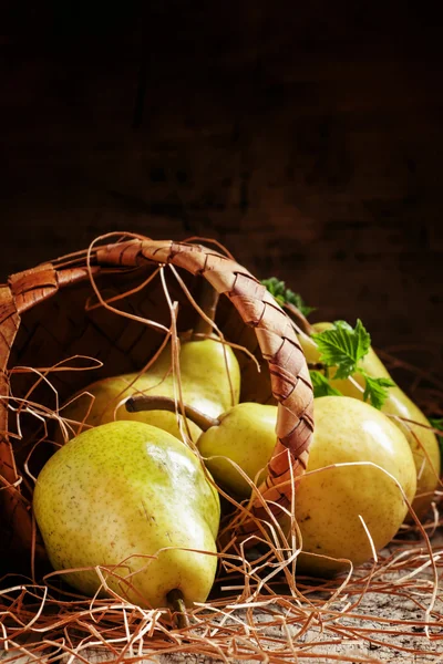 Reife herbstliche gelbe Birnen aus einem Weidenkorb gegossen — Stockfoto