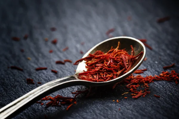 Saffron in a spoon on a dark background — Stock Photo, Image