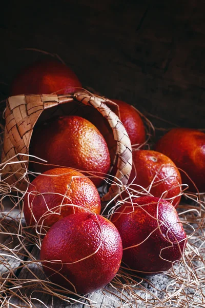 Червоні кров'яні апельсини виливаються з плетеного кошика — стокове фото
