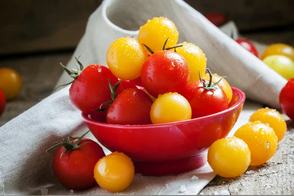 Tomates cherry rojos y anaranjados en un bol rojo — Foto de Stock