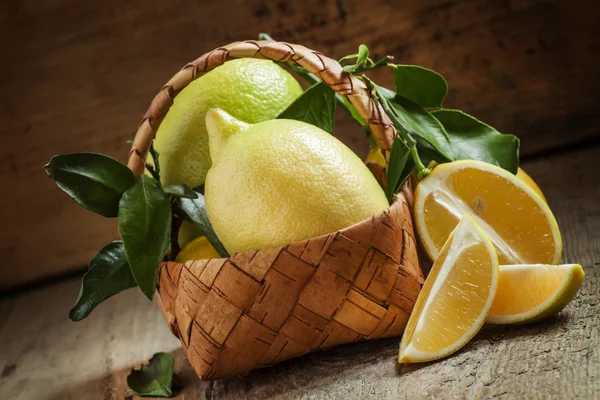 Limões frescos com folhas em uma cesta de vime — Fotografia de Stock