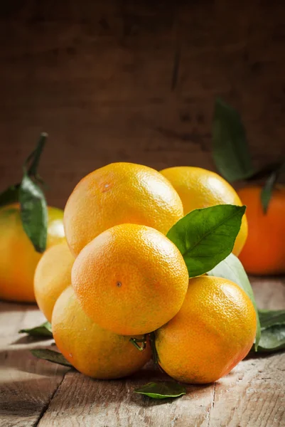 Tangerines dengan daun pada latar belakang kayu tua — Stok Foto