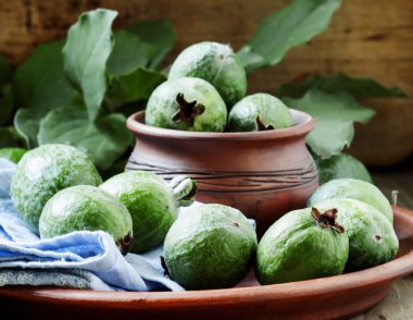 Eski ahşap masa üzerinde mavi peçete ile Taze yeşil feijoa kil kase 