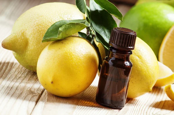 Olio essenziale di limone e limoni freschi sul vecchio fondo di legno — Foto Stock