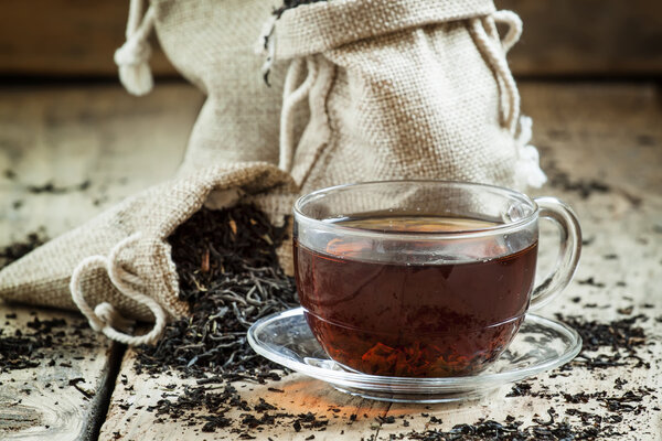 Glass transparent cup of black tea and dry tea in bags 