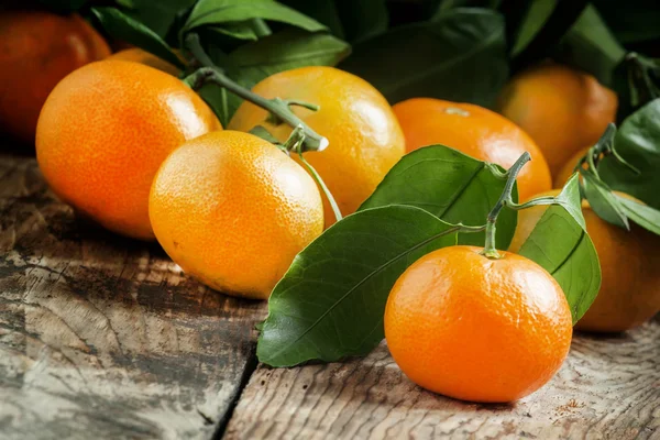 Tangerinas com folhas no velho fundo de madeira — Fotografia de Stock