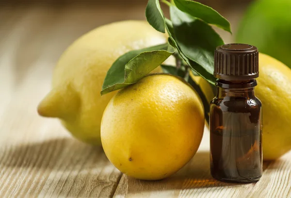 Essential oil of lemon and fresh lemons on the old wooden background — Stock Photo, Image