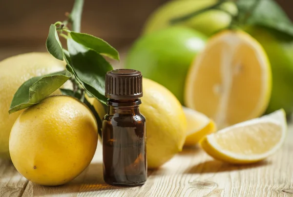 Óleo essencial de limão e limões frescos no velho fundo de madeira — Fotografia de Stock