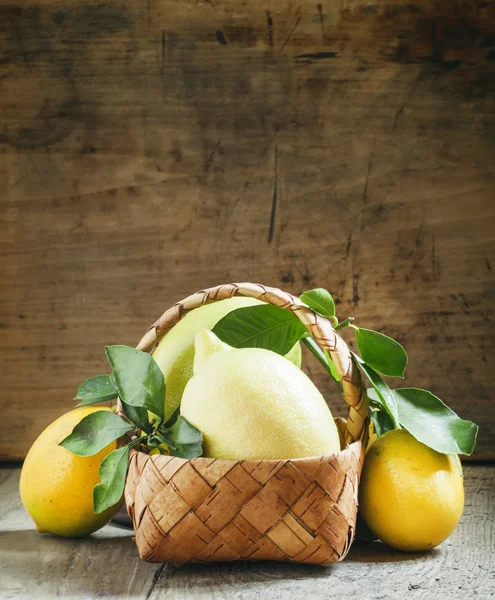 Φρέσκα λεμόνια με φύλλα σε ένα καλάθι λυγαριά — Φωτογραφία Αρχείου