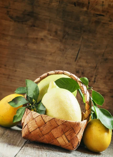 Limones frescos con hojas en una canasta de mimbre — Foto de Stock