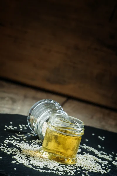 Óleo de gergelim no vaso e sementes de gergelim polvilhadas — Fotografia de Stock