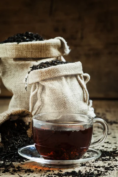 Copa de vidrio transparente de té negro y té seco en bolsas — Foto de Stock