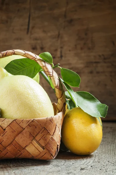 Limones frescos con hojas en una canasta de mimbre — Foto de Stock