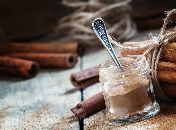 Canela moída em um frasco de vidro com uma colher — Fotografia de Stock