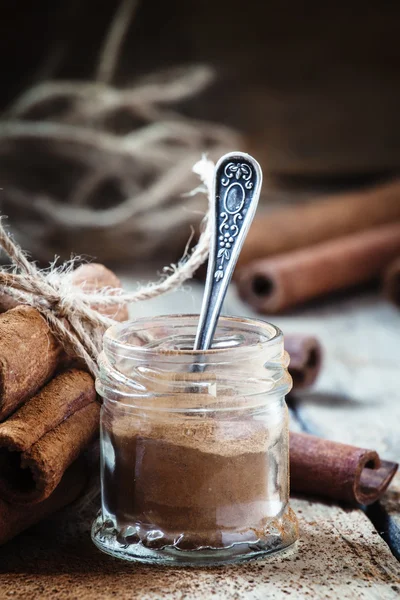 Ground cinnamon in a glass jar with a spoon — Stock Photo, Image