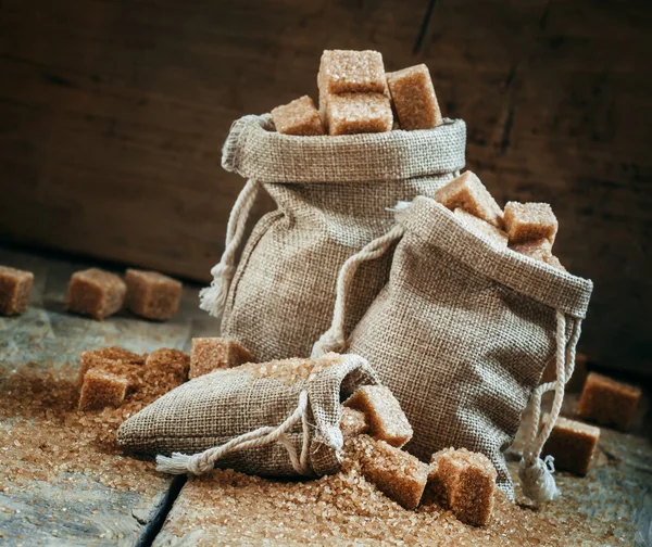 Caña de azúcar morena cubos y cristales en sacos de arpillera —  Fotos de Stock