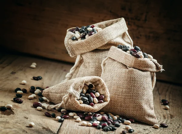 Feijão seco multicolorido em sacos de serapilheira — Fotografia de Stock