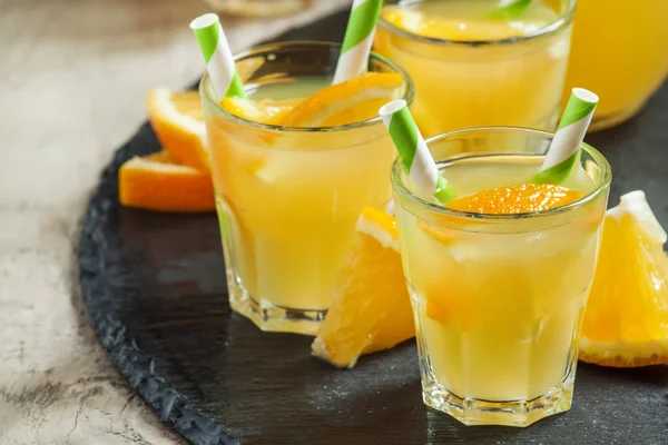 Orange pít v malých skleničkách s pruhovanou brčka a džbán — Stock fotografie