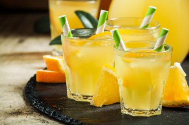 Turuncu içecek çizgili payet ve sürahi ile küçük bardaklarda