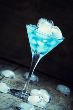 Bir martini cam kalp şeklinde buz ile mavi kokteyl 
