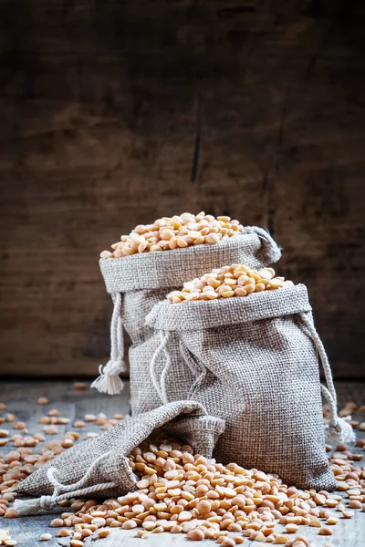 Ervilhas amarelas secas em sacos de serapilheira — Fotografia de Stock