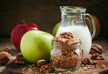 Baked muesli with nuts, milk jug, green and red apples
